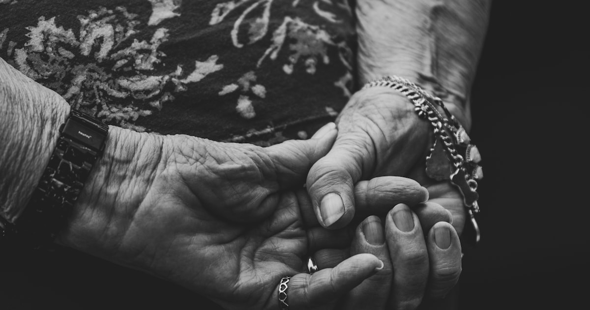 Older woman holding the hand of a younger woman in a caring gesture