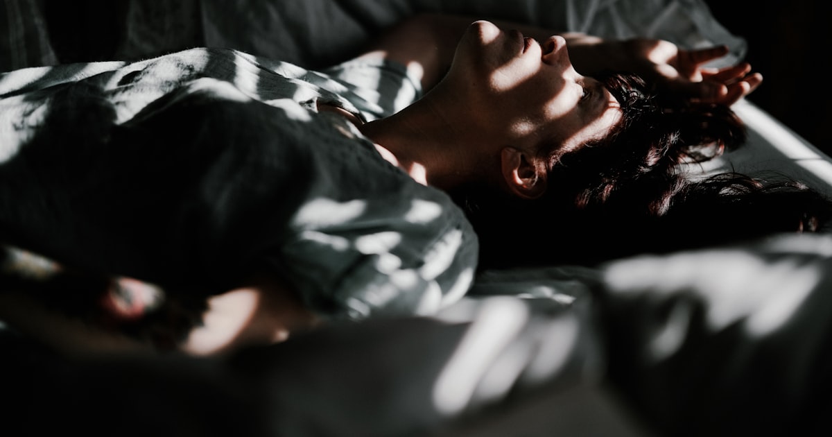 Person laying in bed with head resting on pillow
